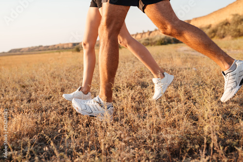 Cropped image of a young couple legs in sneakers running
