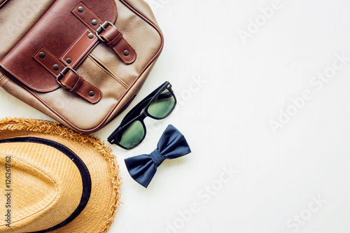Men's accessories outfits with leather bag, sunglasses, hat, and bow tie, top view, flat lay on wooden board background 