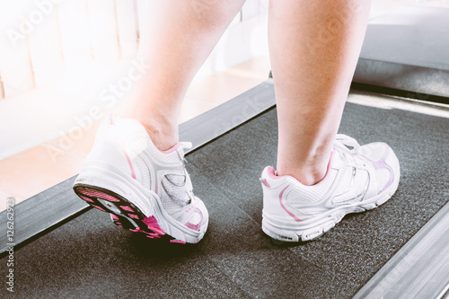 Woman's muscular legs on treadmill