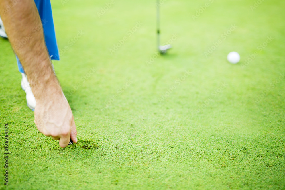 Фотография Golf player repairing divot