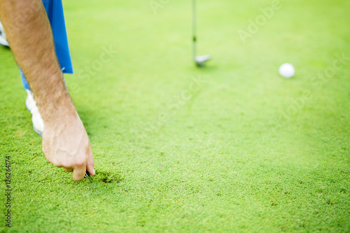 Фотография Golf player repairing divot
