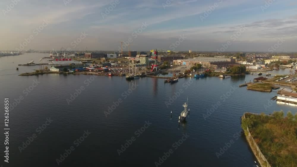 Aerial flying towards Amsterdam North across river IJ, toward hip area in development called the NDSM werf. Aerial flying towards Amsterdam North across river IJ, toward hip area in development called the NDSM werf.