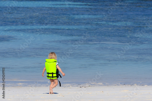 Little girl and green life jacket against sea background at Tachai island, Similan Islands National Park, Phang Nga, Thailand.