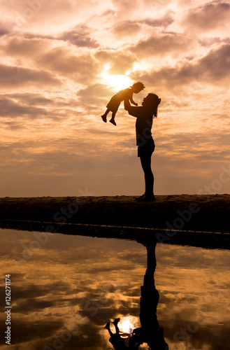 Reflection Silhouette of mother with her toddler against the sun