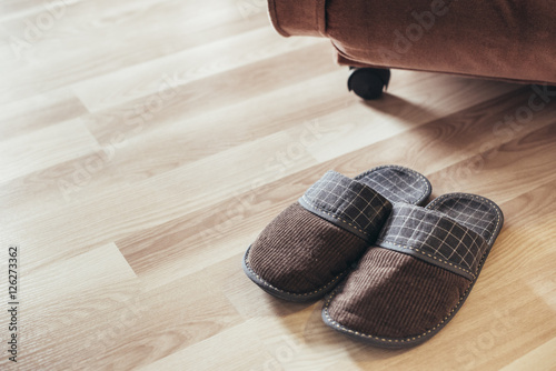 Male slippers in front of the chair