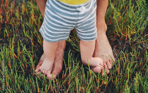 Ножки маленького ребенка и папы стоят на траве