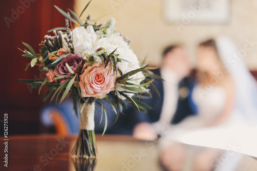 Свадебный букет на фоне молодоженов 