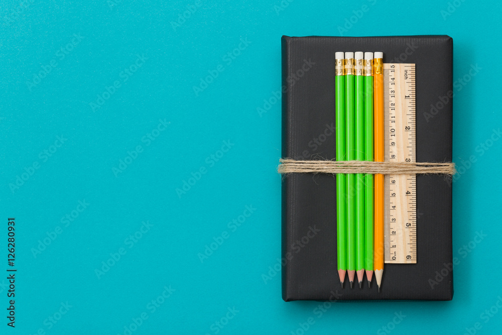Colorful school and office supplies  - pencils and ruler on black book and blue background. Top view with copy space.