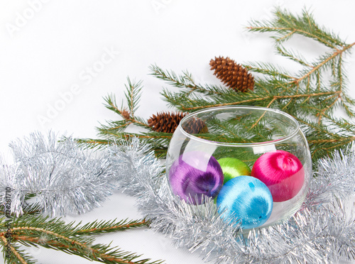 christmas balls in glass vase among tinsel on white background