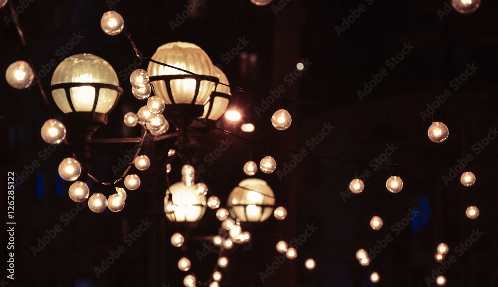 Glowing lanterns and light bulbs in dark at night