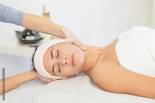 Young woman enjoying facial massage at spa salon.Facial massage