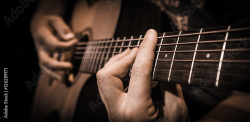 Close up hands on the strings of a guitar photo
