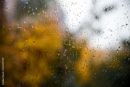 raindrops on the glass from the window overlooking the blurred autumn landscape / reflection weather