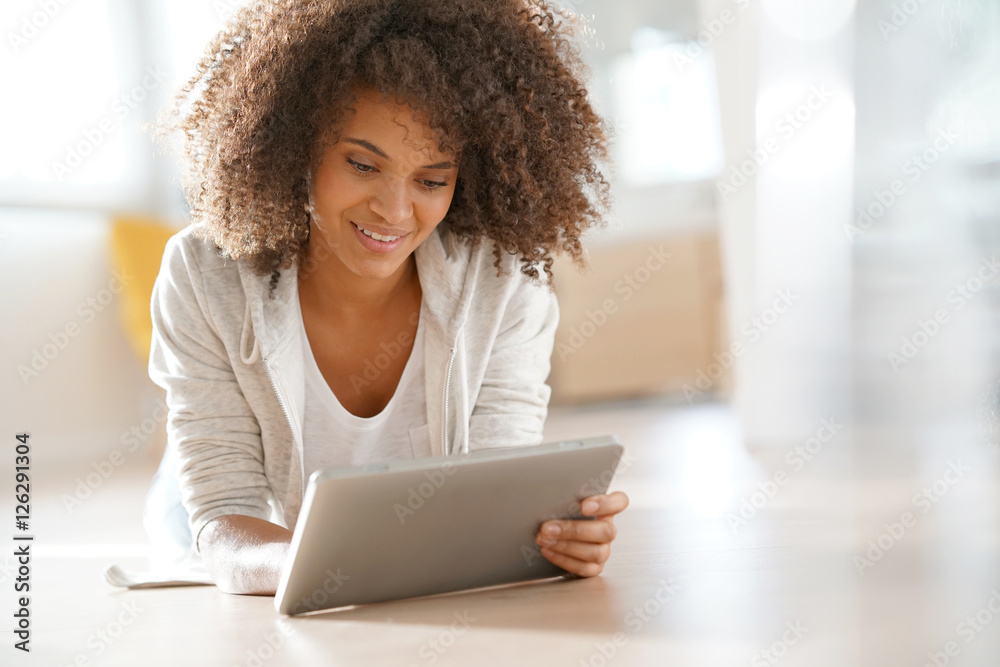 Relaxed mixed-race girl laying on floor connected with tablet Relaxed mixed-race girl laying on floor connected with tablet
