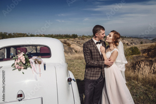 elegant stylish groom kissing gently gorgeous bride, at black ca