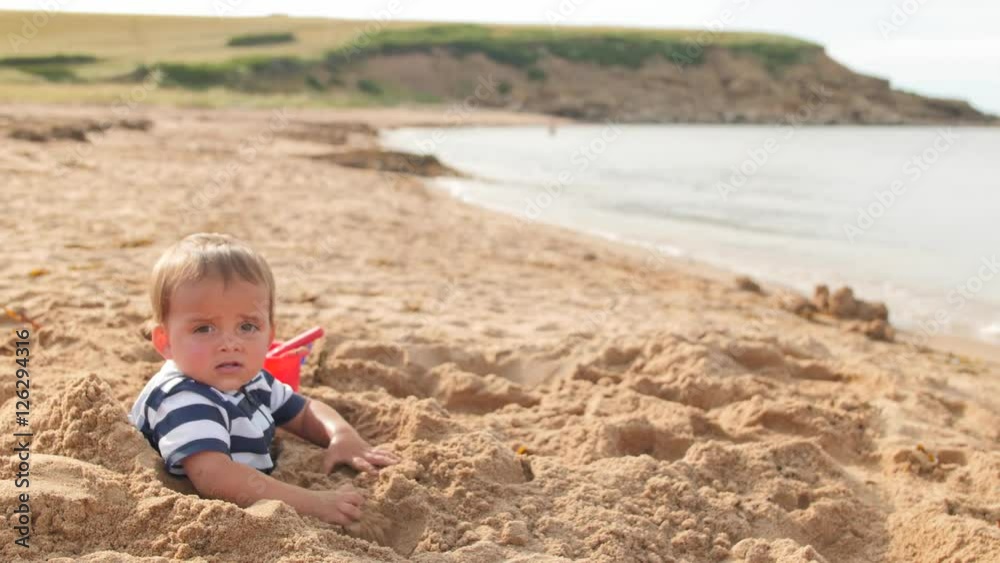 A boy buried in a beautiful sandy ocean beach