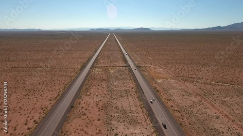 High aerial shot of vehicles on a long straight highway in a desert