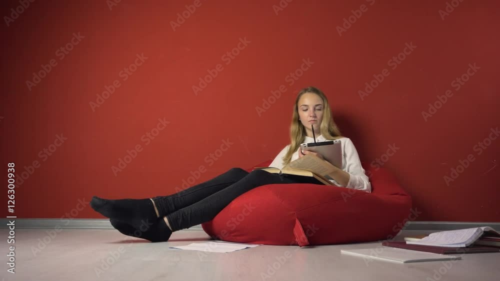 Young student girl studying sitting on the bag-chair near books and tablet pc Young student girl studying sitting on the bag-chair near books and tablet pc