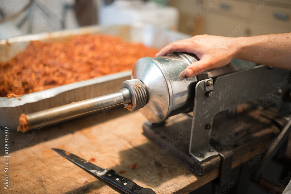 Man making sausages the traditional way using sausage filler. Man making sausages the traditional way using sausage filler.
