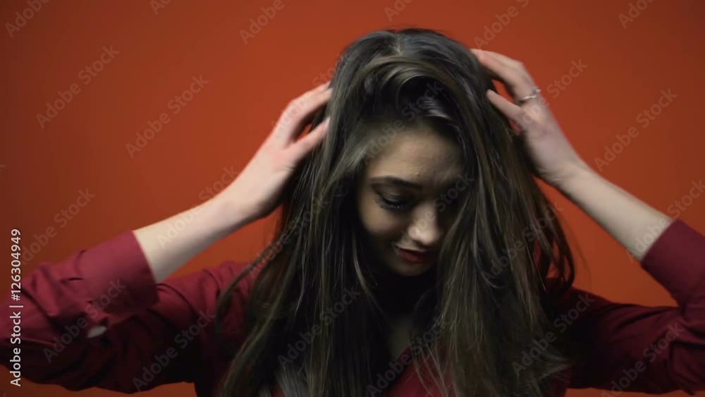 Beautiful brunette girl posing to camera before red background Beautiful brunette girl posing to camera before red background