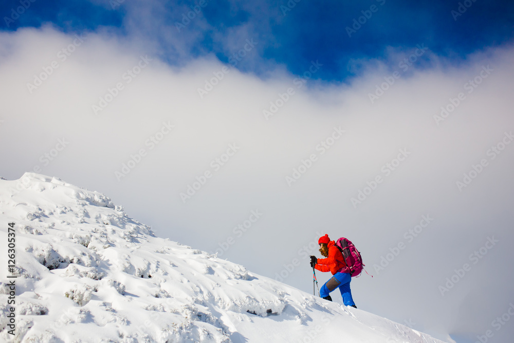 Climber with backpack walks on a snowy slope.