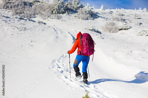 Girl with backpack walking on snow in the mountains.