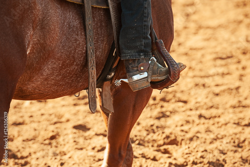 close-up of a spur og the horserider sitting on the horse with cowboy boot