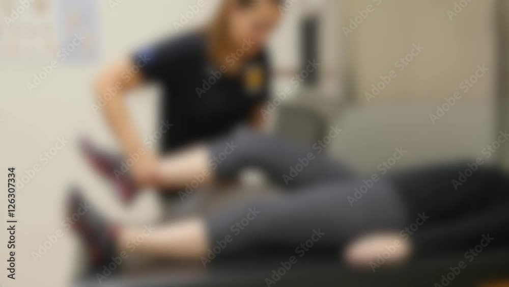 Out of focus shot of a nurse streching girls leg Out of focus shot of a nurse streching girls leg