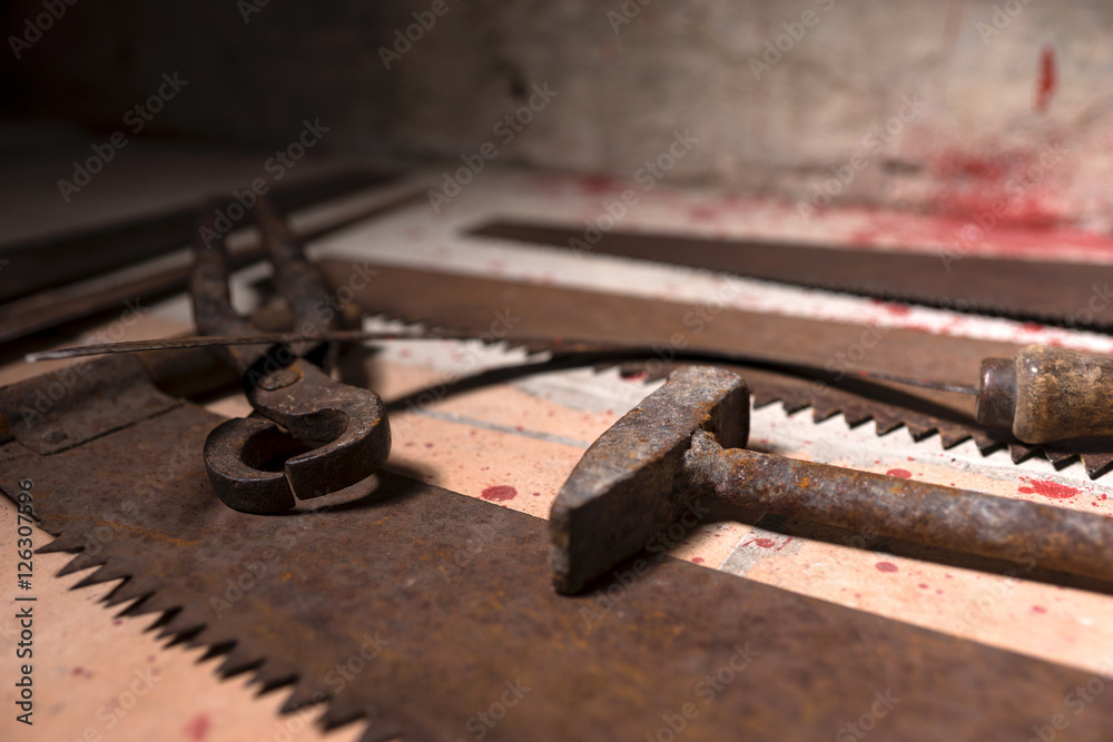 Close up of saws, sickles and other devices on the bloody floor Close up of saws, sickles and other devices on the bloody floor