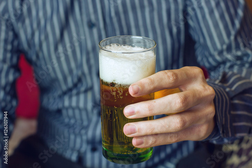 Fotografi Mano de un hombre joven sujetando un vaso de cerveza
