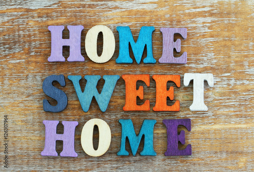 Home sweet home written with colorful letters on rustic wooden surface
