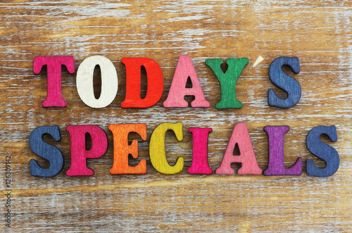 Today's specials written with colorful letters on rustic wooden surface
