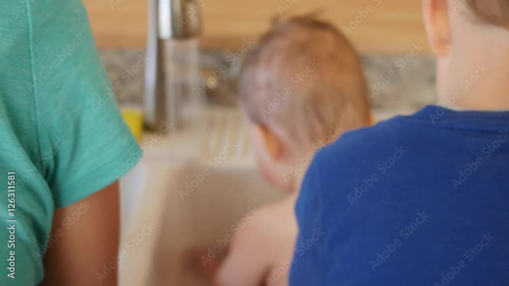 A mother giving a baby a bath in kitchen sink A mother giving a baby a bath in kitchen sink