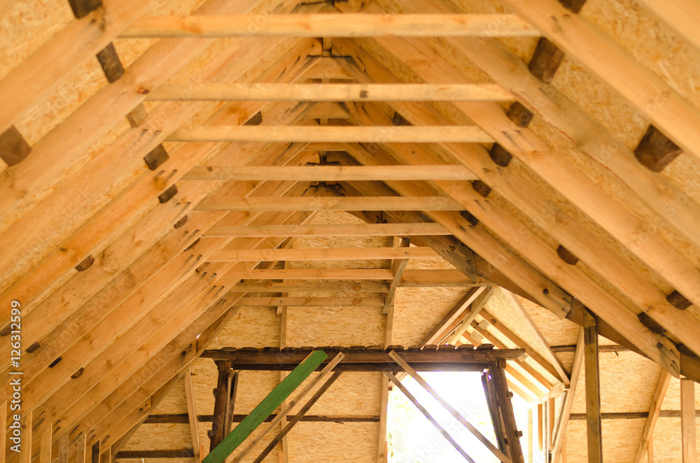 Raising roof truss to second story of new residential construction. Interior view of a wooden roof structure. roof preparation of OSB. Raising roof truss to second story of new residential construction. Interior view of a wooden roof structure. roof preparation of OSB.