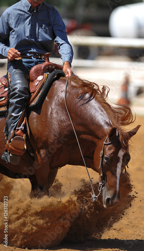 A close up view of a rider and horse sliding in the dirt