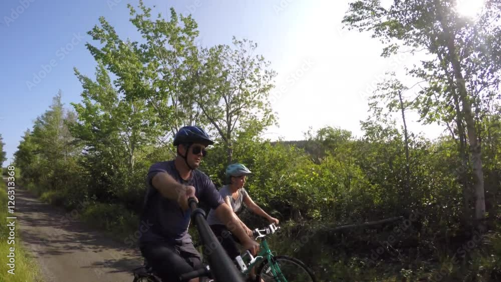 Fun shot of a couple biking in green forest on bike trail Fun shot of a couple biking in green forest on bike trail