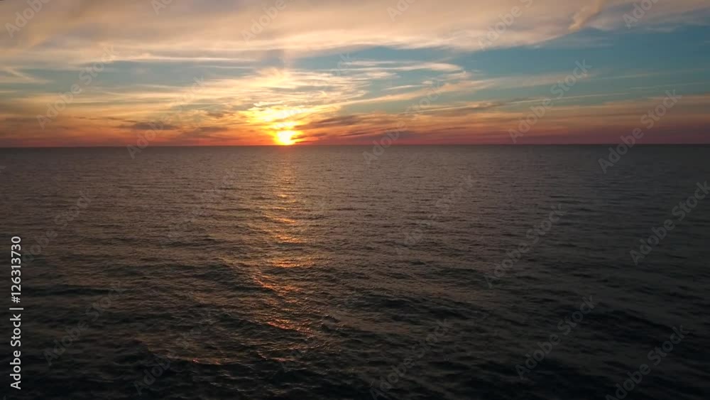 Aerial descending shot of a beautiful ocean sunset above sea