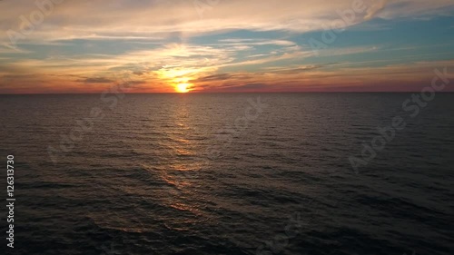 Aerial descending shot of a beautiful ocean sunset above sea photo