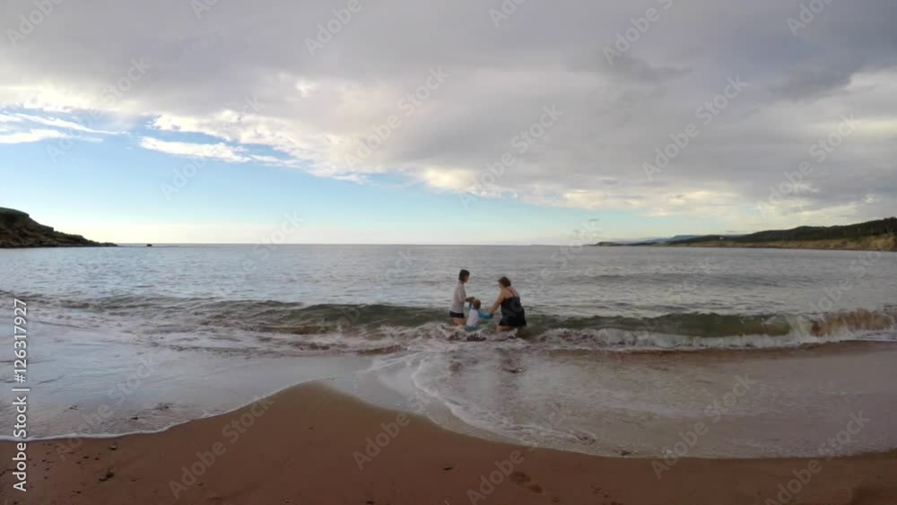 Family playing in ocean waves on sandy beach Family playing in ocean waves on sandy beach