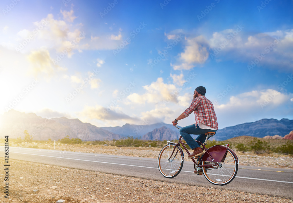 man riding bike into nevada sunset on empty highway