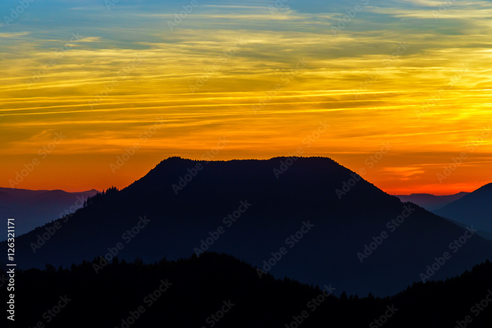 Idyllic sunset landscape with silhouettes of mountains and vivid