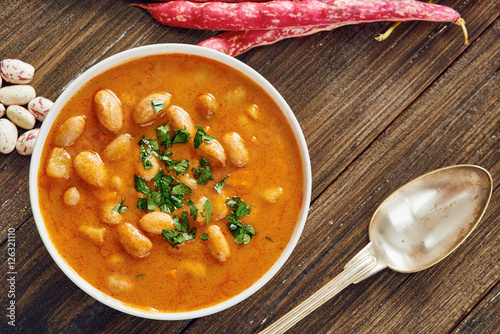 Bean soup in white bowl and spoon on wooden table