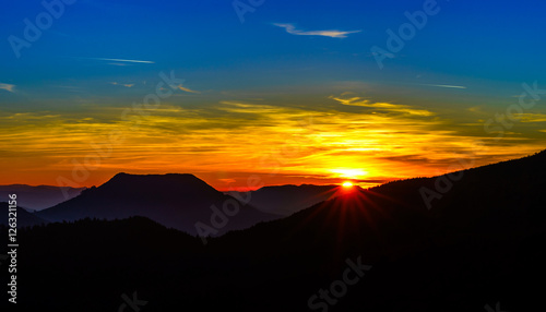 Idyllic sunset landscape with silhouettes of mountains and vivid