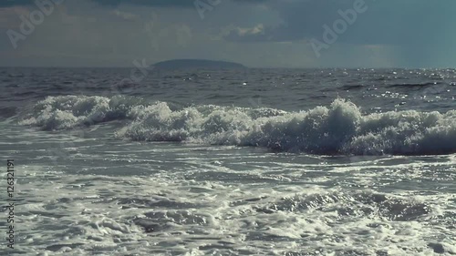 Slow motion shot of waves falling on a shore in the evening photo