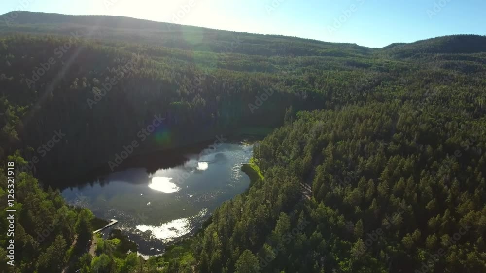 Aerial high shot over trees and beautiful mountain lake at sunset Aerial high shot over trees and beautiful mountain lake at sunset
