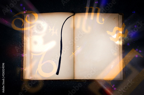Photo Old magic book with glowing zodiac symbols
