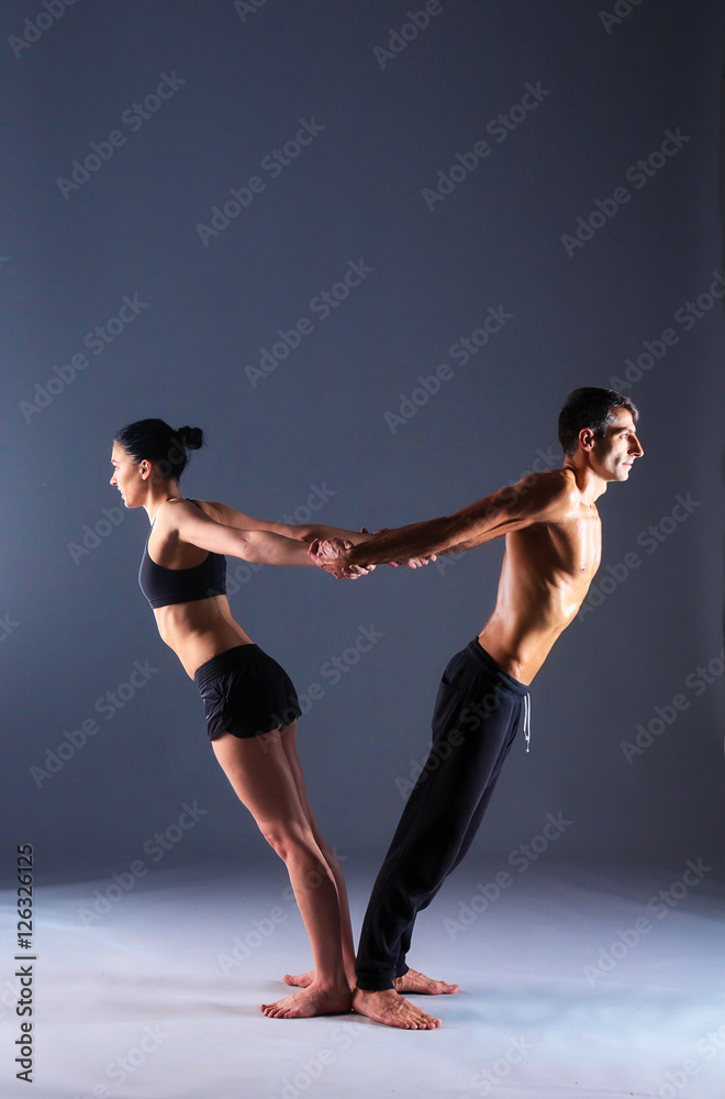 Fototapeta premium Young couple practicing acro yoga in studio together