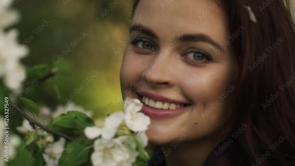 Young pretty smiling caucasian woman in jeans jacket standing near blooming spring tree. Youth, freshness, beauty, happiness concept. Young pretty smiling caucasian woman in jeans jacket standing near blooming spring tree. Youth, freshness, beauty, happiness concept.