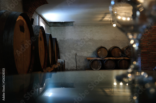 Piwnice winiarni - szklany stół z kieliszkiem przygotowany do degustacji. © konik60