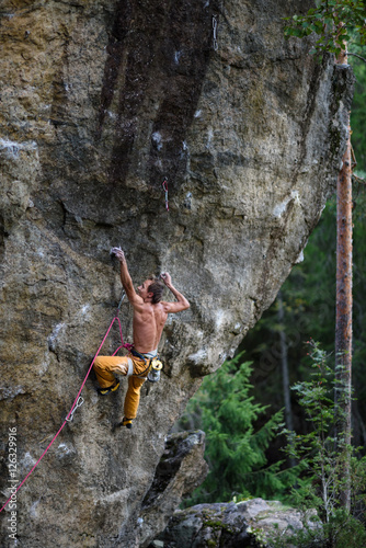 Young man climbing a rock with belay. Extreme rock climbing. Outdoor lifestyle. 